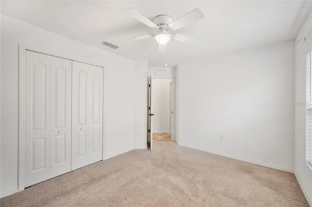 an empty room with a ceiling fan and a window