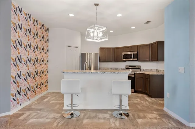 a kitchen with kitchen island granite countertop a stove top oven a sink dishwasher a dining table and chairs with wooden floor