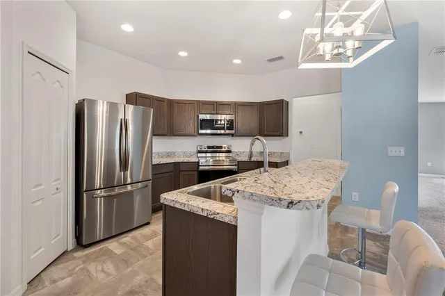 a kitchen with stainless steel appliances granite countertop a refrigerator and a stove top oven