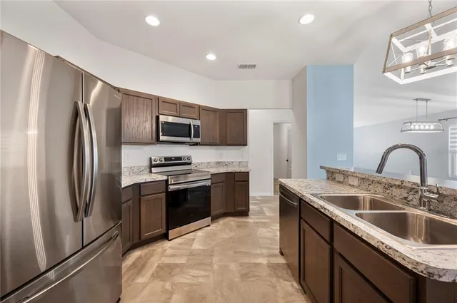 a kitchen with stainless steel appliances granite countertop a sink stove and refrigerator