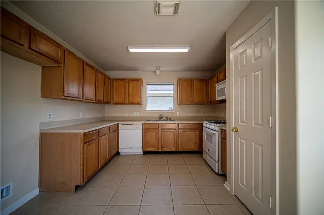 a kitchen with a sink a stove top oven and cabinetry