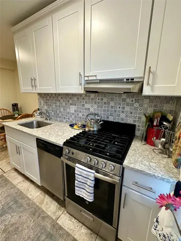 a kitchen with granite countertop a stove sink and cabinets