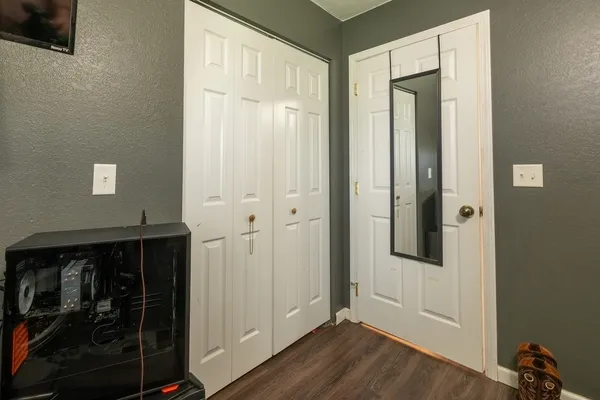 a view of a elevator and an empty room with wooden floor