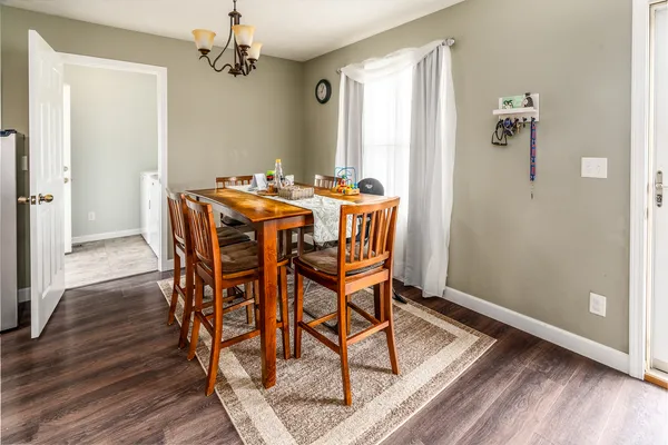 a dining room with wooden floor a chandelier a wooden table and chairs