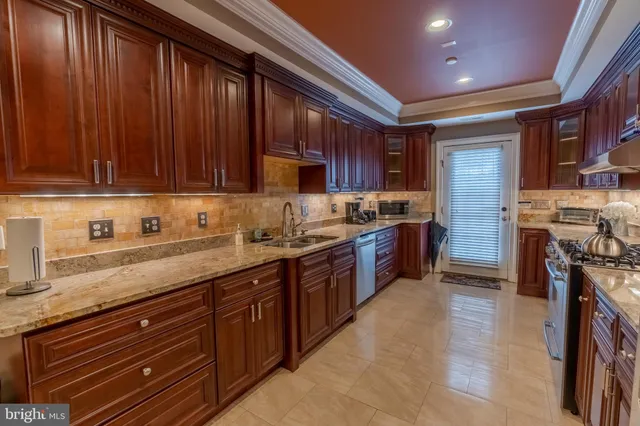 a kitchen with stainless steel appliances granite countertop wooden cabinets a sink and dishwasher a stove top oven with wooden floor