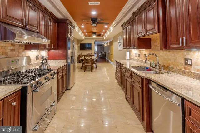 a kitchen with stainless steel appliances granite countertop a sink a stove and a wooden cabinets