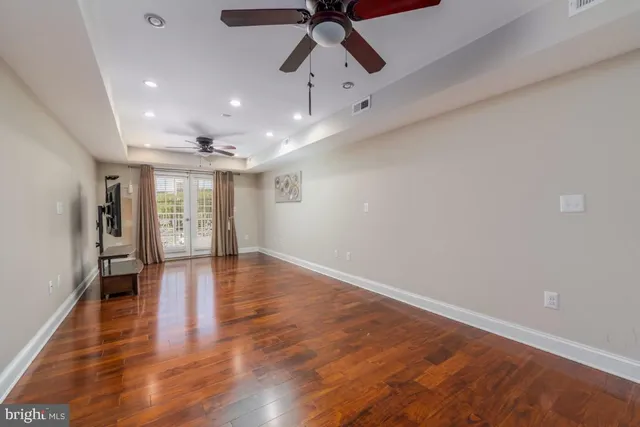an empty room with wooden floor chandelier and windows