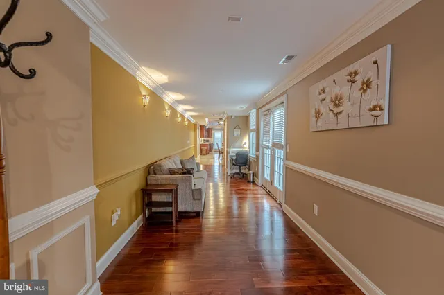 a hallway with wooden floor stairs and furniture