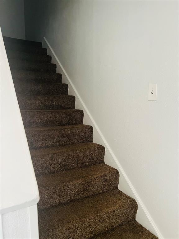 6320 Midway Road, Unit C Springtown, TX 76082 - Photo 9 of 11 Staircase featuring brown carpeting, white risers, and a white handrail