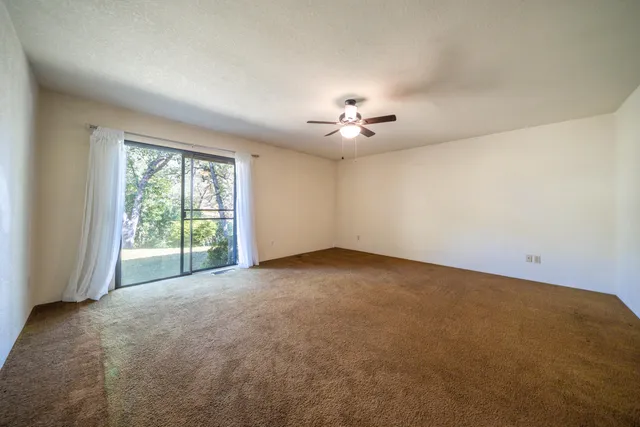 an empty room with a chandelier fan and windows
