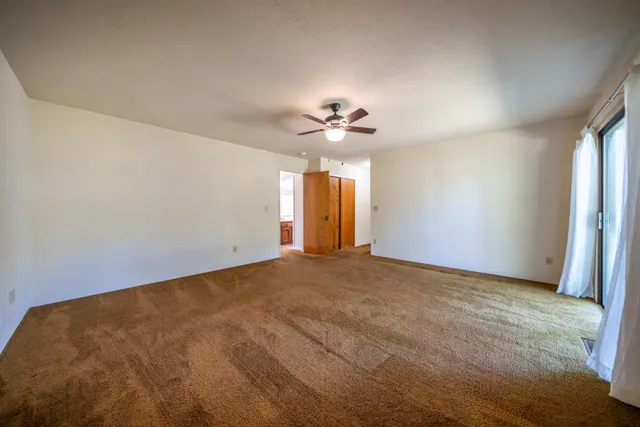 an empty room with a chandelier fan and closet