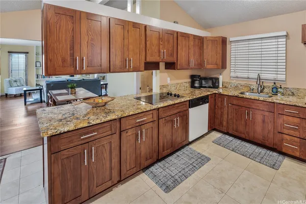 a kitchen with kitchen island granite countertop a sink dishwasher stove and cabinets