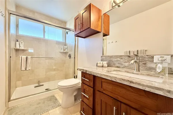 a bathroom with a granite countertop sink a toilet and shower