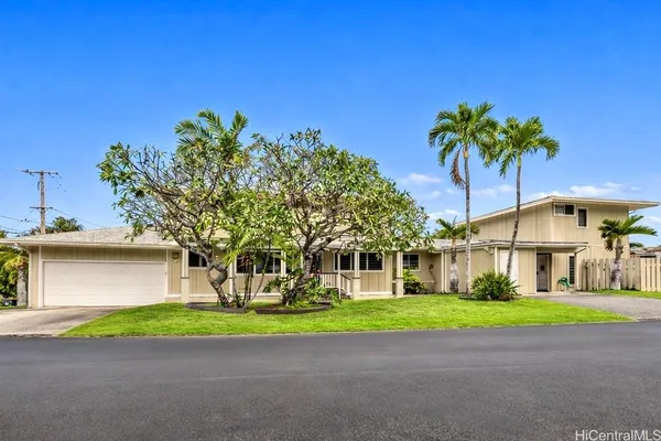 a view of a house with a big yard and palm trees