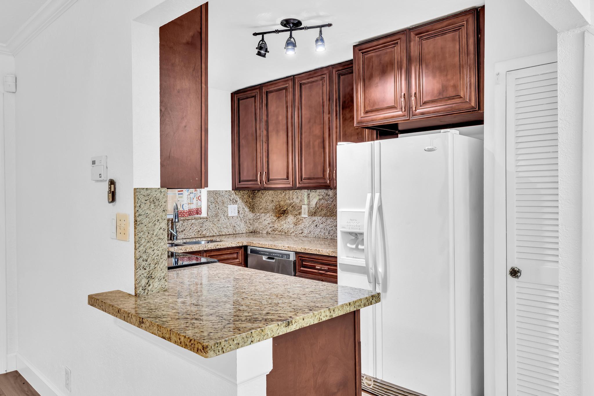 1291 Northwest 13th Street, Unit 445D Boca Raton, FL 33486 - Photo 23 of 50 a kitchen with stainless steel appliances granite countertop a refrigerator a stove and a sink with wooden floor