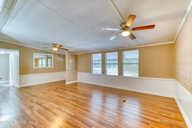 a view of an empty room with window and wooden floor
