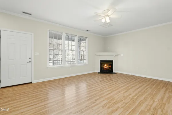 a view of an empty room with wooden floor fireplace and a window