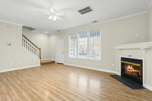 an empty room with wooden floor fireplace and windows