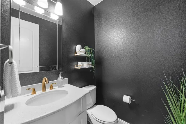 a bathroom with a granite countertop sink and a mirror with toilet