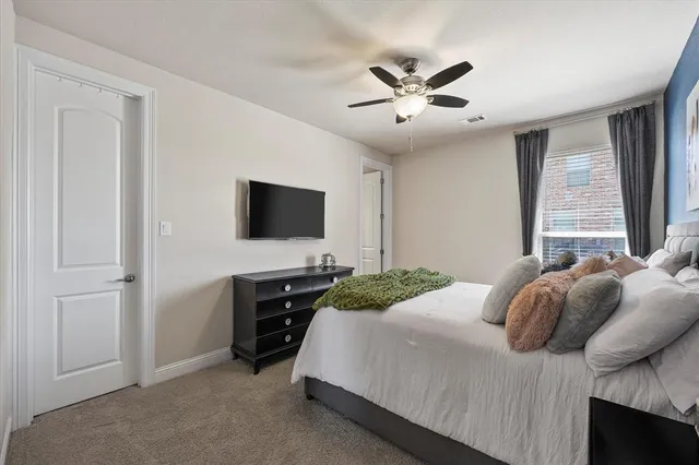 a bedroom with a bed and a flat tv screen on dresser