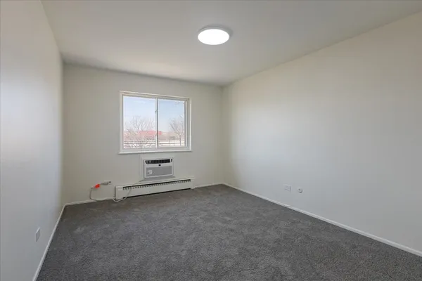 an empty room with windows and exposed radiator