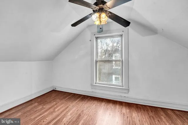 an empty room with wooden floor chandelier fan and windows