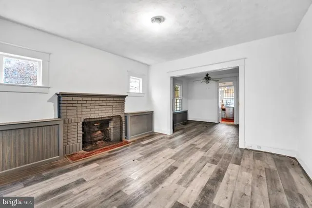 an empty room with wooden floor fireplace and windows