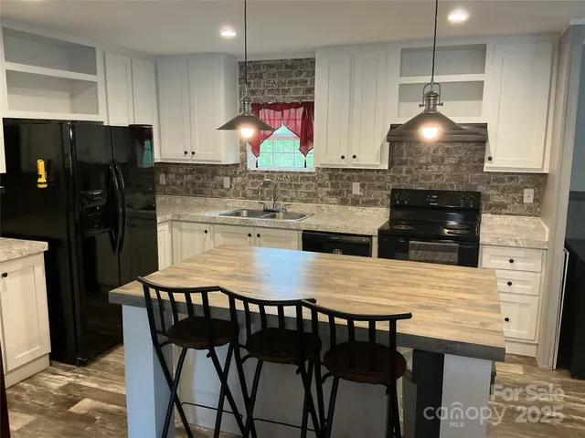 a kitchen with stainless steel appliances granite countertop a stove a refrigerator a sink a dining table and chairs