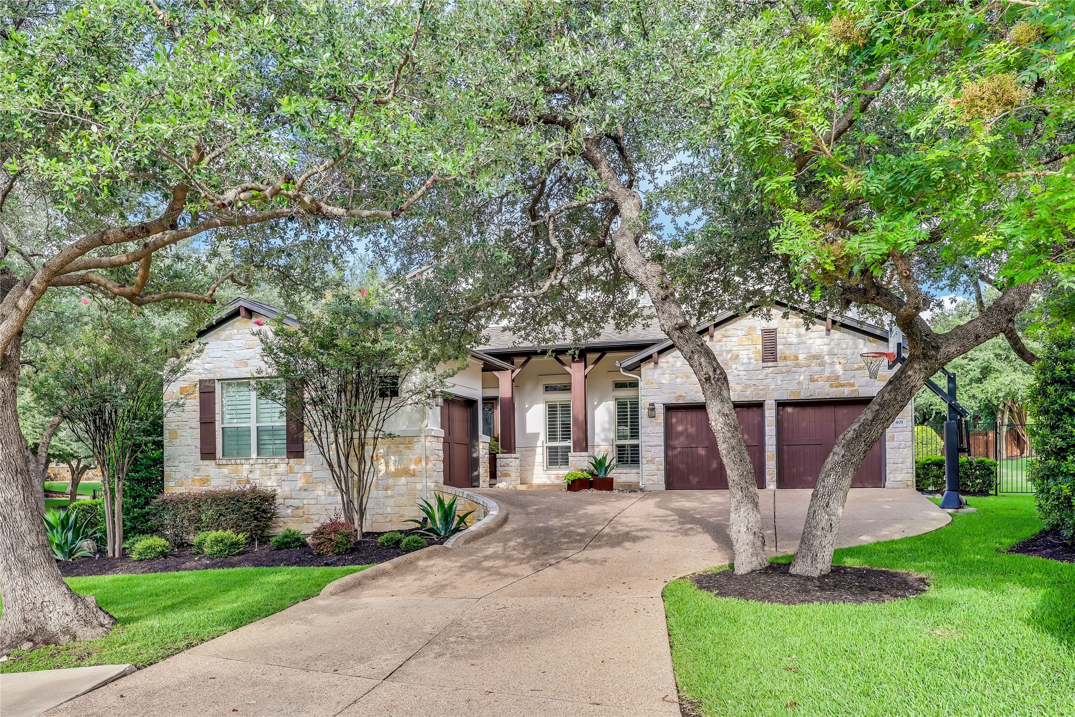401 Bluff View Road Cedar Park, TX 78613 - Photo 1 of 40 Mature trees shade this inviting stone-clad residence, featuring a curved driveway and dual garage doors.