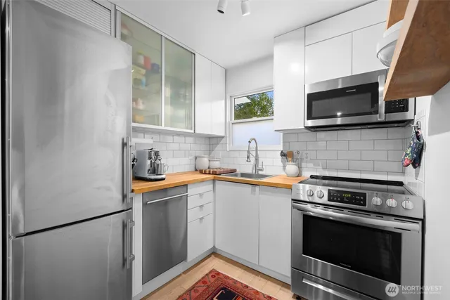 a kitchen with stainless steel appliances a stove microwave and sink