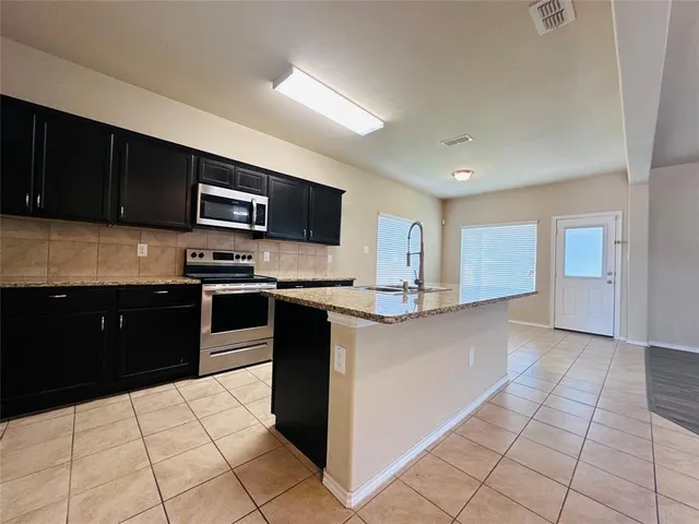 a kitchen with stainless steel appliances granite countertop a refrigerator and a stove top oven
