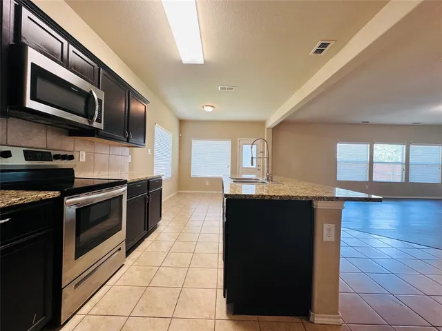 a kitchen with stainless steel appliances granite countertop a stove a sink and a microwave