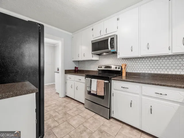 a kitchen with white cabinets granite counter tops and a stove