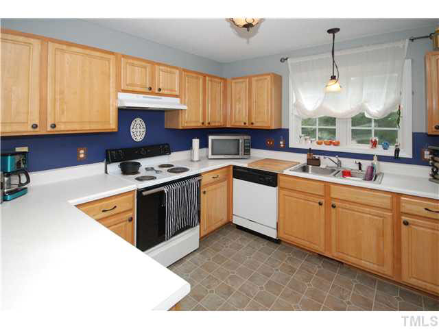 4712 Valley Stream Drive Raleigh, NC 27616 - Photo 9 of 25 a kitchen with stainless steel appliances granite countertop a stove a sink dishwasher and white cabinets with wooden floor