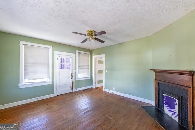 a view of an empty room with window and wooden floor