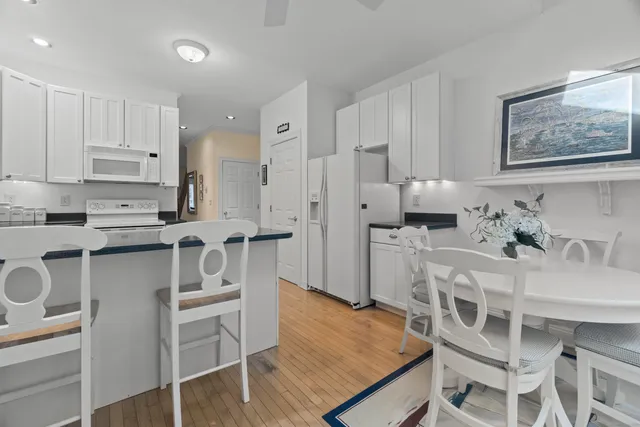 a kitchen with stainless steel appliances kitchen island granite countertop a table chairs cabinets and wooden floor