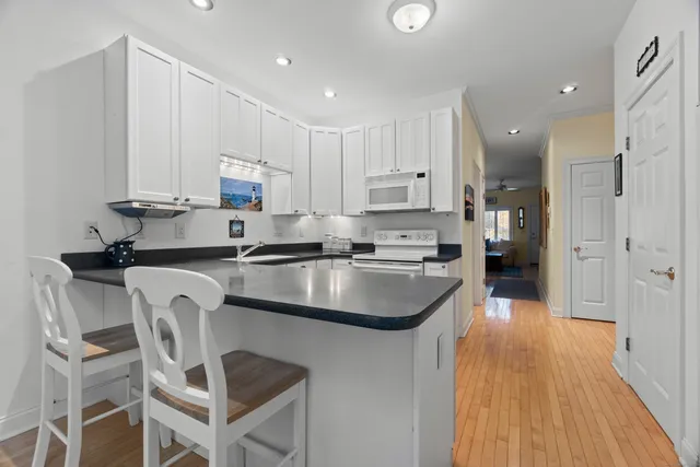 a kitchen with stainless steel appliances granite countertop a sink a stove a refrigerator cabinets and chairs