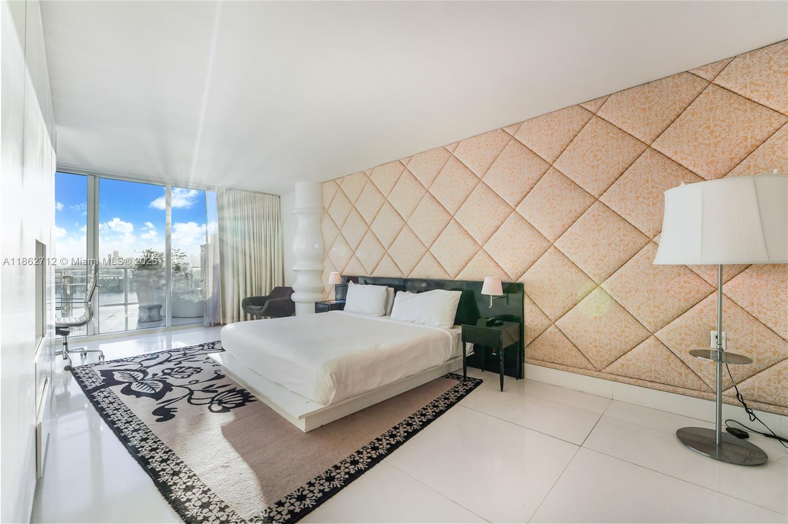 1100 West Avenue, Unit TS4 Miami Beach, FL 33139 - Photo 9 of 18 a bedroom with a bed and a lamp next to a large window