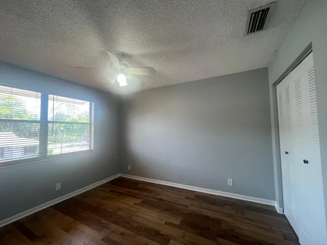 an empty room with wooden floor and windows