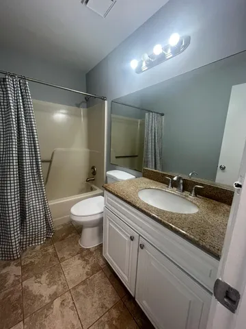 a bathroom with a granite countertop sink a toilet and a mirror