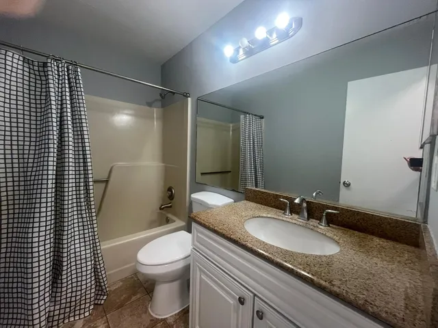 a bathroom with a granite countertop sink toilet a mirror and shower