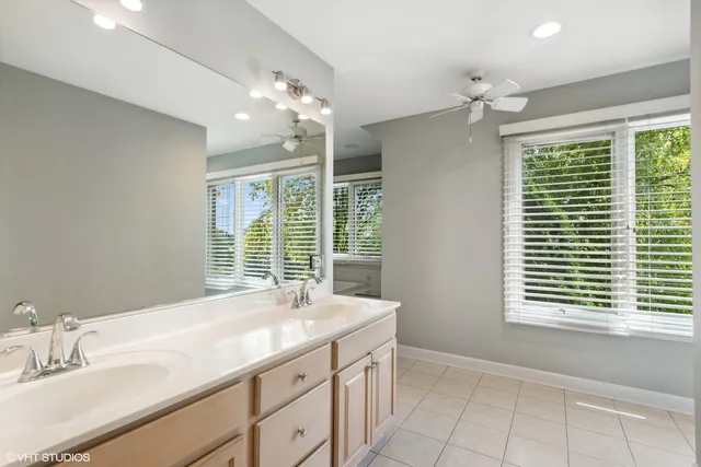a bathroom with a granite countertop sink a large mirror and a bathtub next to a window