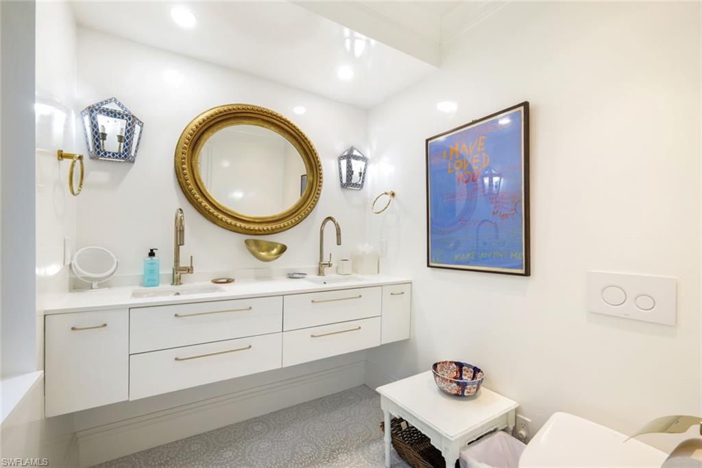 295 6th Street North Naples, FL 34102 - Photo 17 of 32 a bathroom with a toilet a sink and a mirror