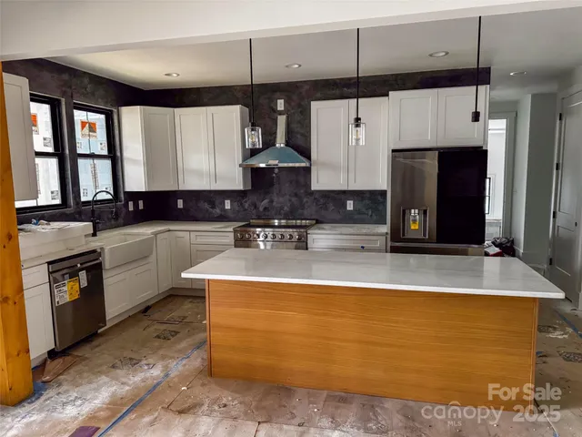 a view of a kitchen with kitchen island a sink a counter top space stainless steel appliances and cabinets