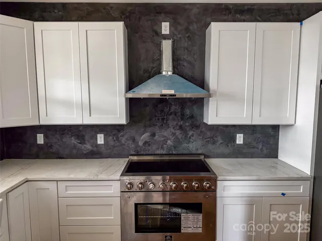 a kitchen with stainless steel appliances granite countertop a stove a refrigerator and a white cabinets