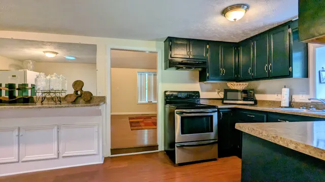 a kitchen with stainless steel appliances kitchen island granite countertop a stove a sink and a refrigerator