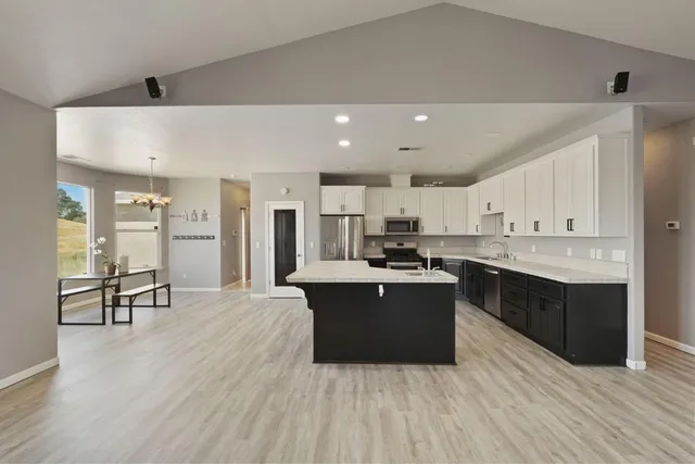 a kitchen with stainless steel appliances granite countertop a refrigerator a sink a stove and oven