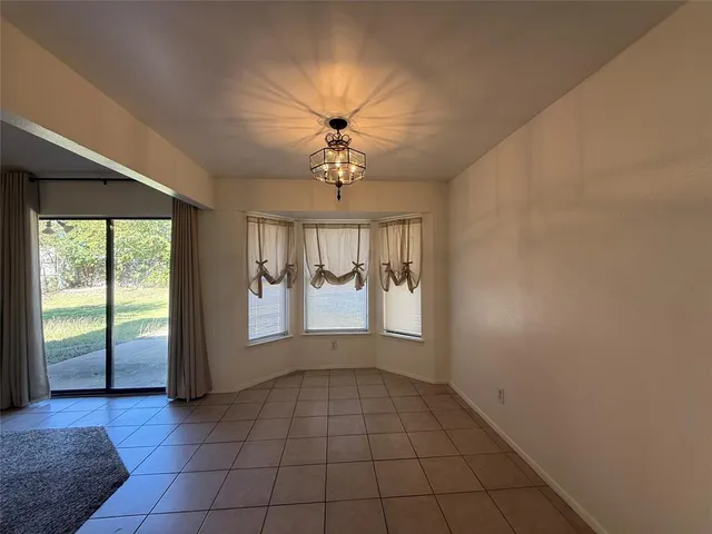 an empty room with windows and chandelier fan