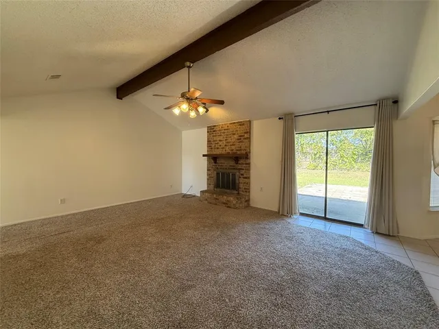 an empty room with chandelier fan and windows