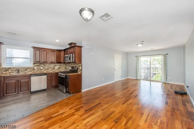 a large kitchen with kitchen island granite countertop a stove top oven a sink a counter space and cabinets